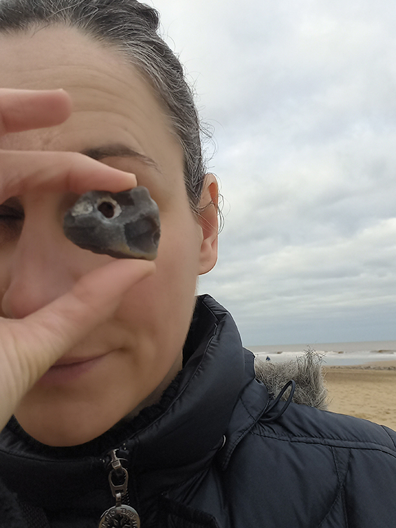 a lady holding a hagstone up to her eye and looking through it
