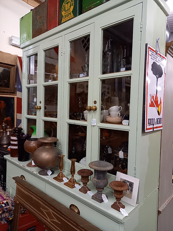 a white dresser showing lots of unusual copper candlesticks